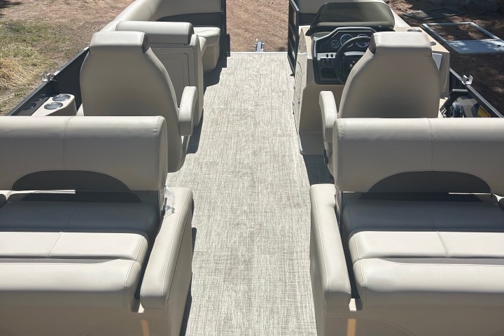 Interior of a pontoon boat with beige seats and a steering console.